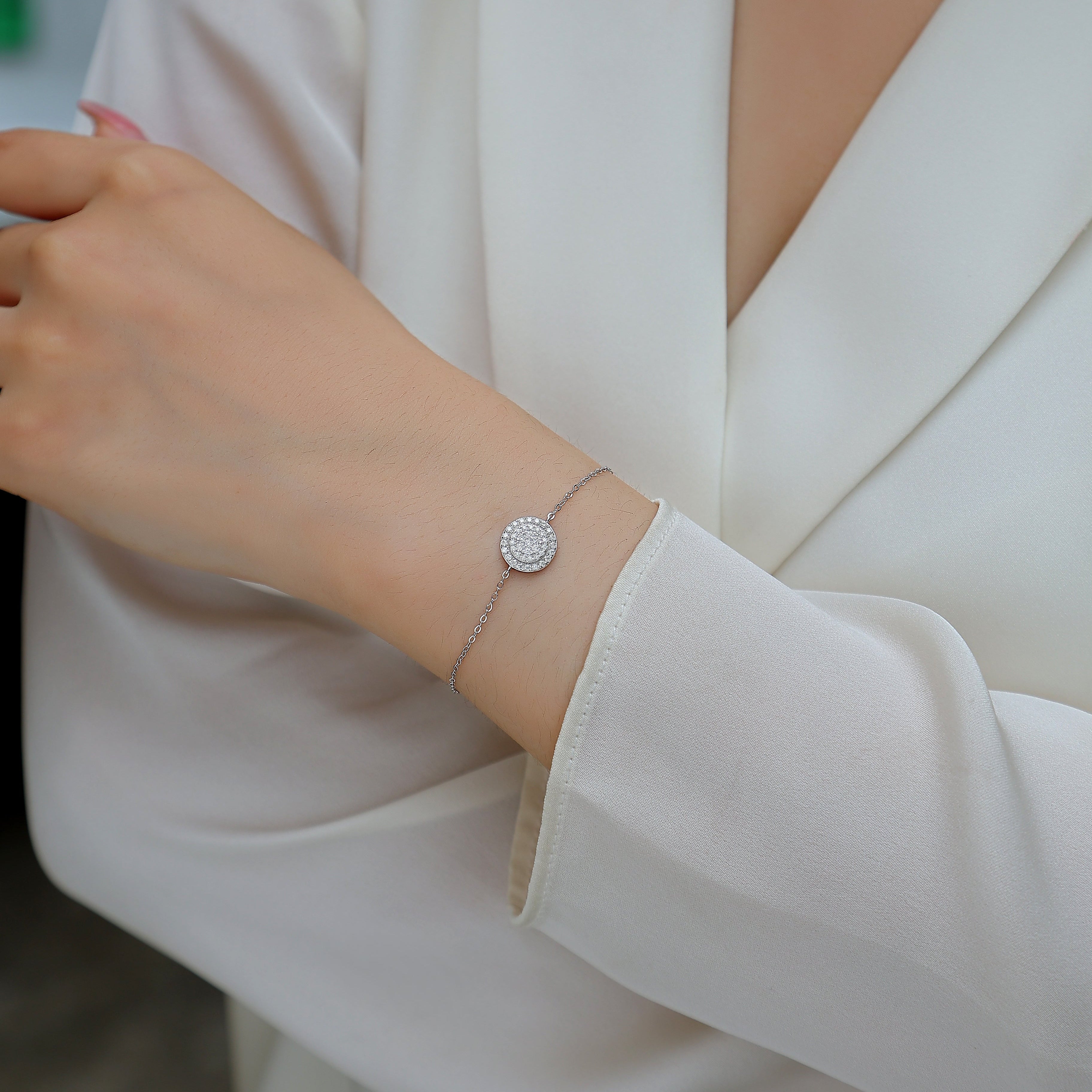 Close-up of a person wearing a silver bracelet with a white blazer.
